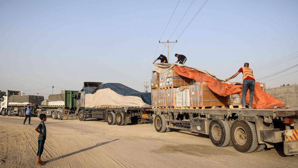 PHOTO: People unload humanitarian aid on a convoy of lorries entering the Gaza Strip from Egypt via the Rafah border crossing on Oct. 21, 2023.