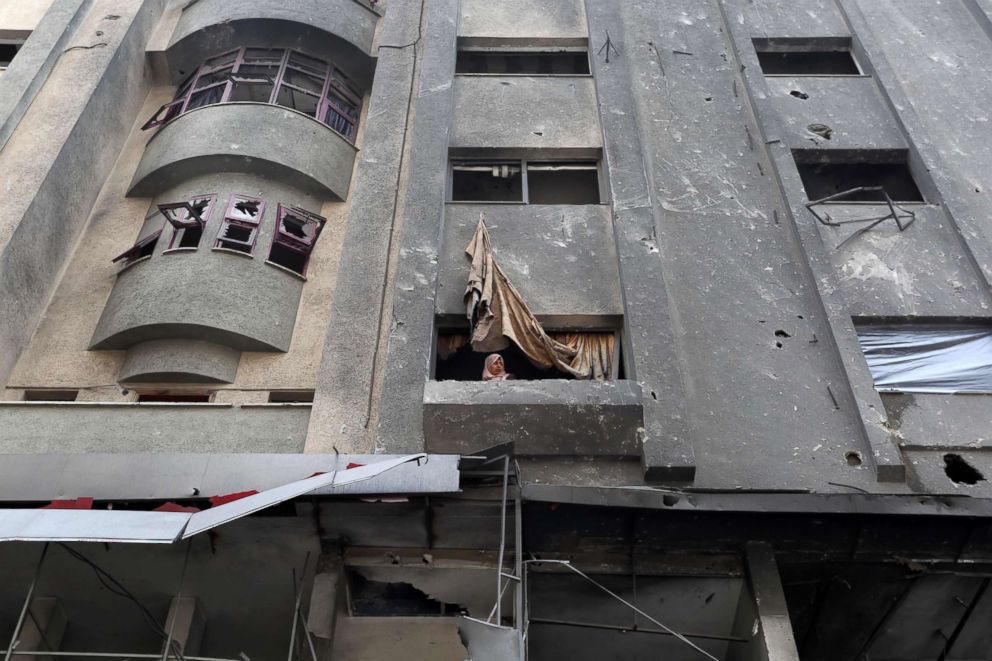 PHOTO: A Palestinian woman looks out the window after Israeli air strikes destroyed buildings in Gaza City on November 14, 2018. 