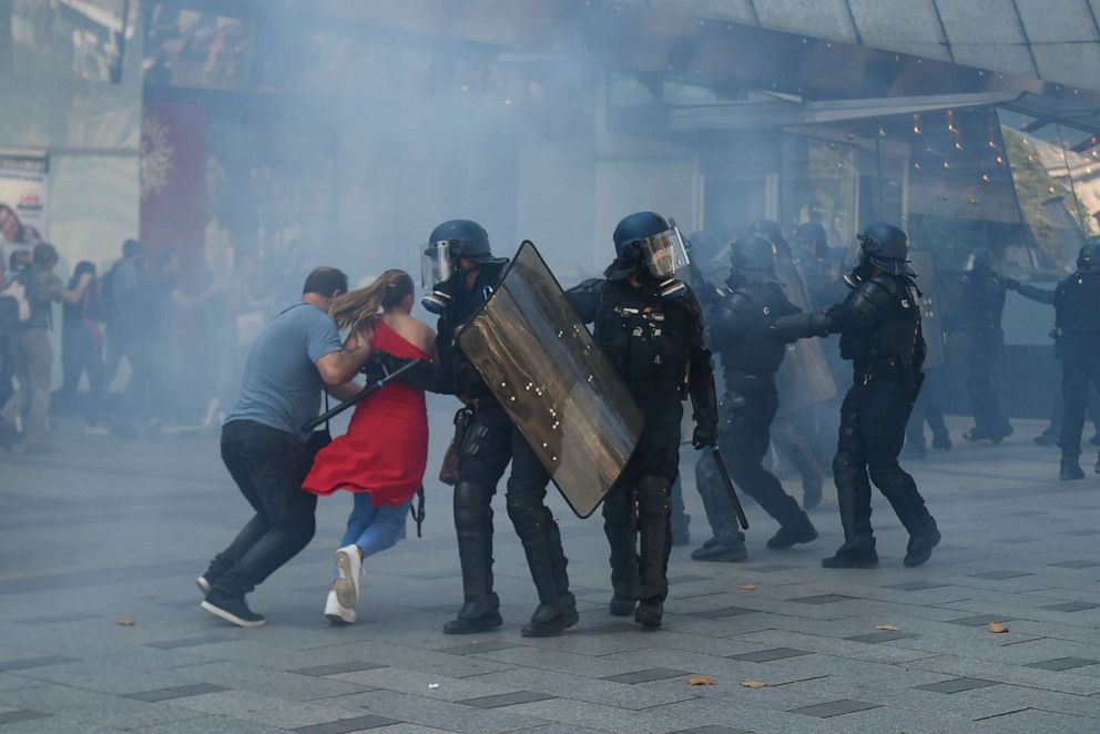 PHOTO: People run among tear gas on the Champs Elysees avenue during an anti-government demonstration called by the "yellow vest" (gilets jaunes) movement, on September 21, 2019 in Paris.