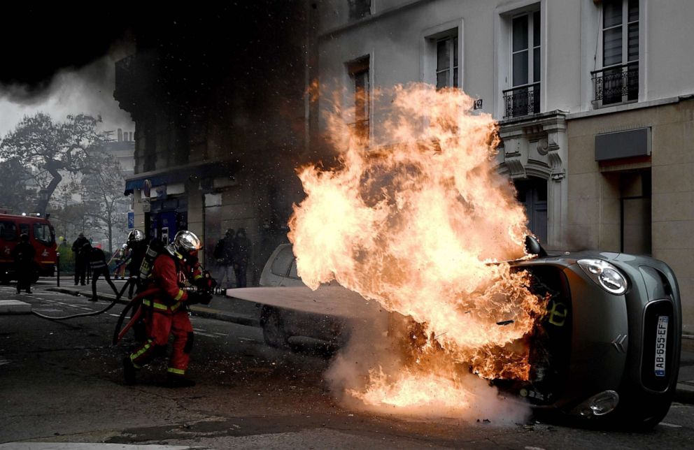 PHOTO: A firefighter tries to extinguish a burning car on place d'Italie in Paris on November 16, 2019, on the sidelines of a demonstration of the "yellow vest" (gilets jaunes) marking the first anniversary of the movement.