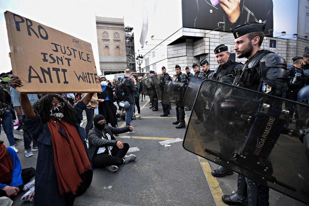 PHOTO: A demonstrator holds a sign reading 'pro justice isn't anti white' in front of French police on the Place de la Concorde, in Paris, June 6, 2020, as part of 'Black Lives Matter' worldwide protests against racism and police brutality.