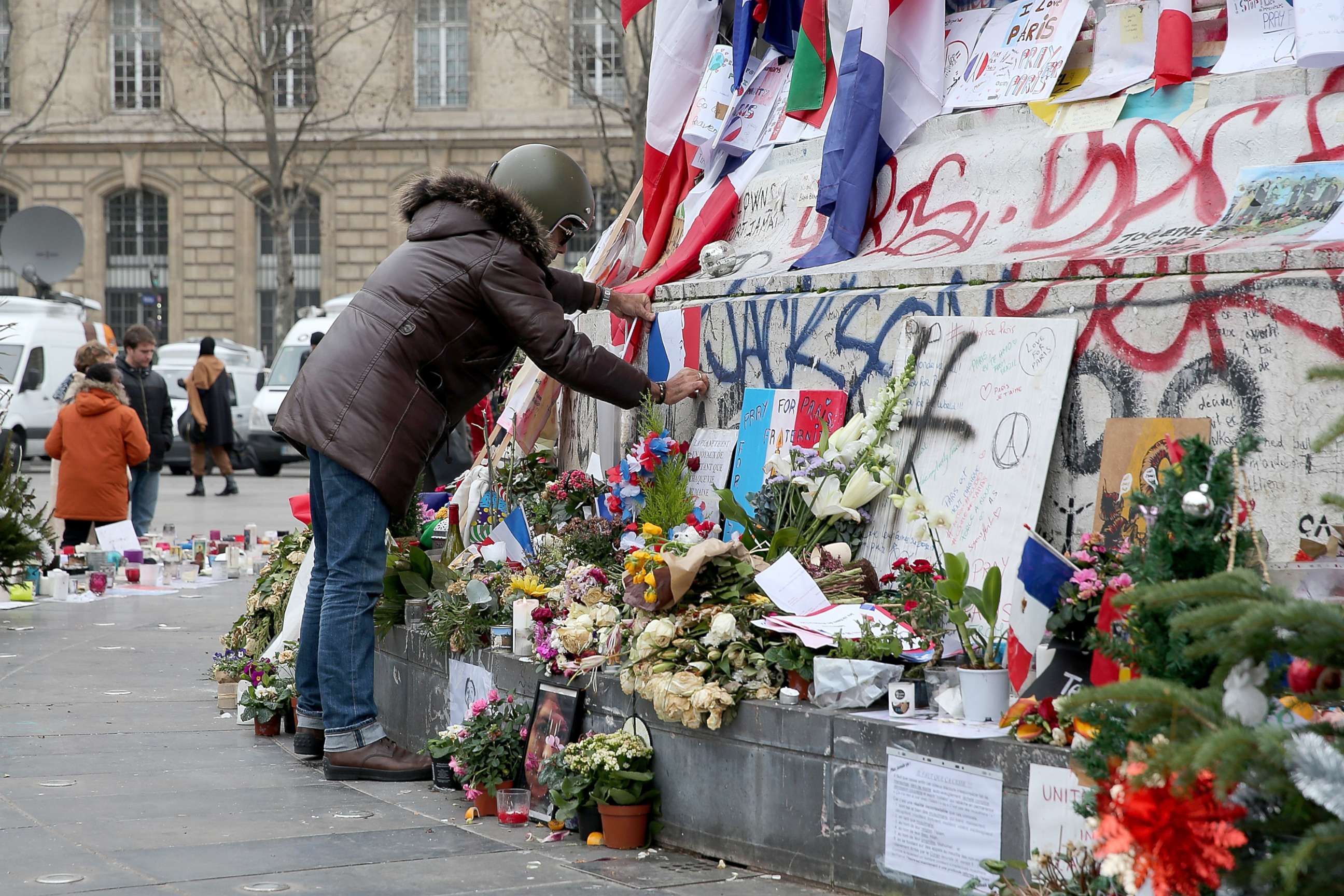 PHOTO: A man  is seen posting a French flag on the monument of the 'Place de la Republique' where people continue to pay tribute to the Paris Attacks victims one month after they occurred, Dec. 13, 2015, in Paris.