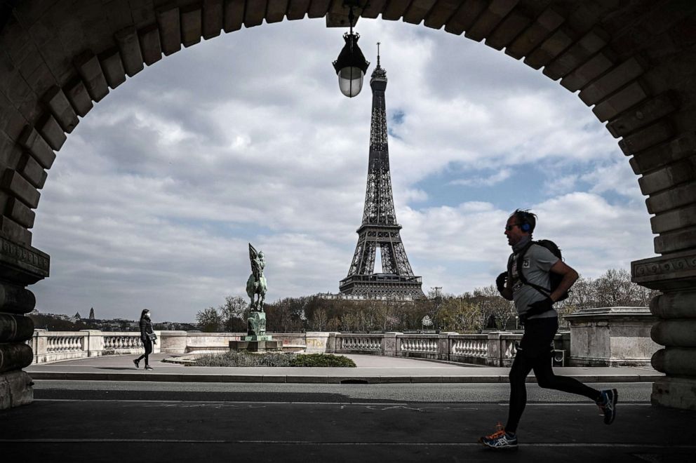 PHOTO: A man jogs on the Bir-Hakeim bridge in front of the Eiffel Tower in Paris on April 2, 2020, during the lockdown in France to stop the spread of COVID-19 (novel coronavirus). 