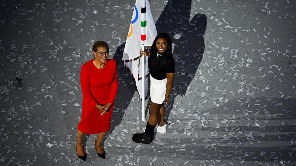 PHOTO: Gymnast Simone Biles of the U.S., wearing a boot, holds the Olympic flag next to Los Angeles Mayor Karen Bass during the Closing Ceremony of the 2024 Paris Olympics, Aug. 11, 2024.