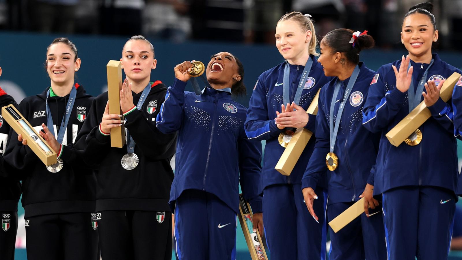 PHOTO: Simone Biles holds her gold medal as she reacts with teammates and next to silver medalists Team Italy after the artistic gymnastics women's team final at the 2024 Paris Olympics, July 30, 2024.