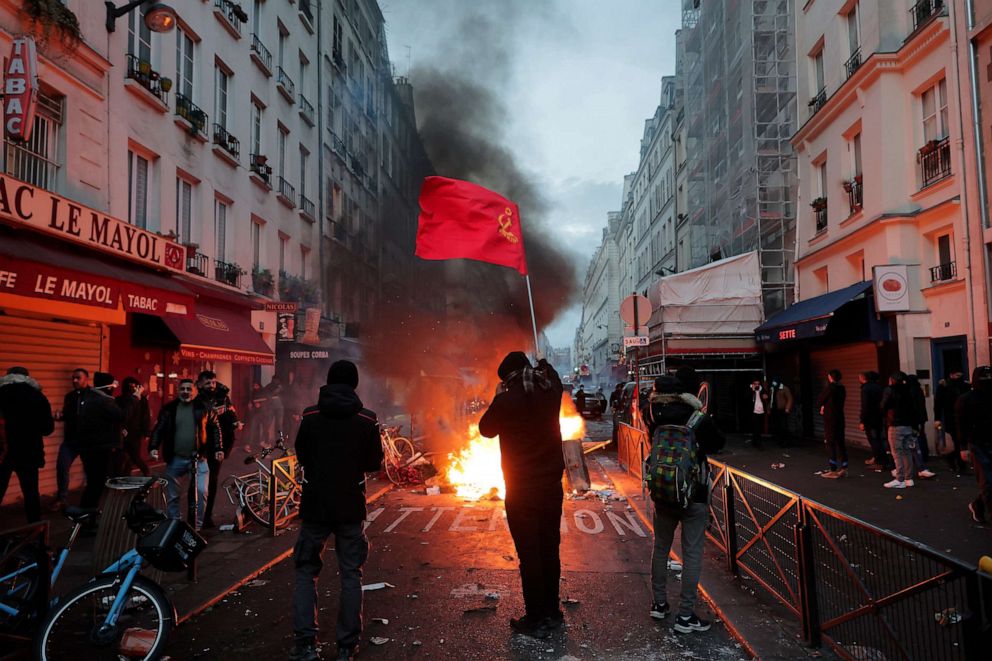 PHOTO: A members of Kurdish community waves the Kurdish communist flags next to a barricade on fire at the crime scene where a shooting took place in Paris, Friday, Dec. 23, 2022.