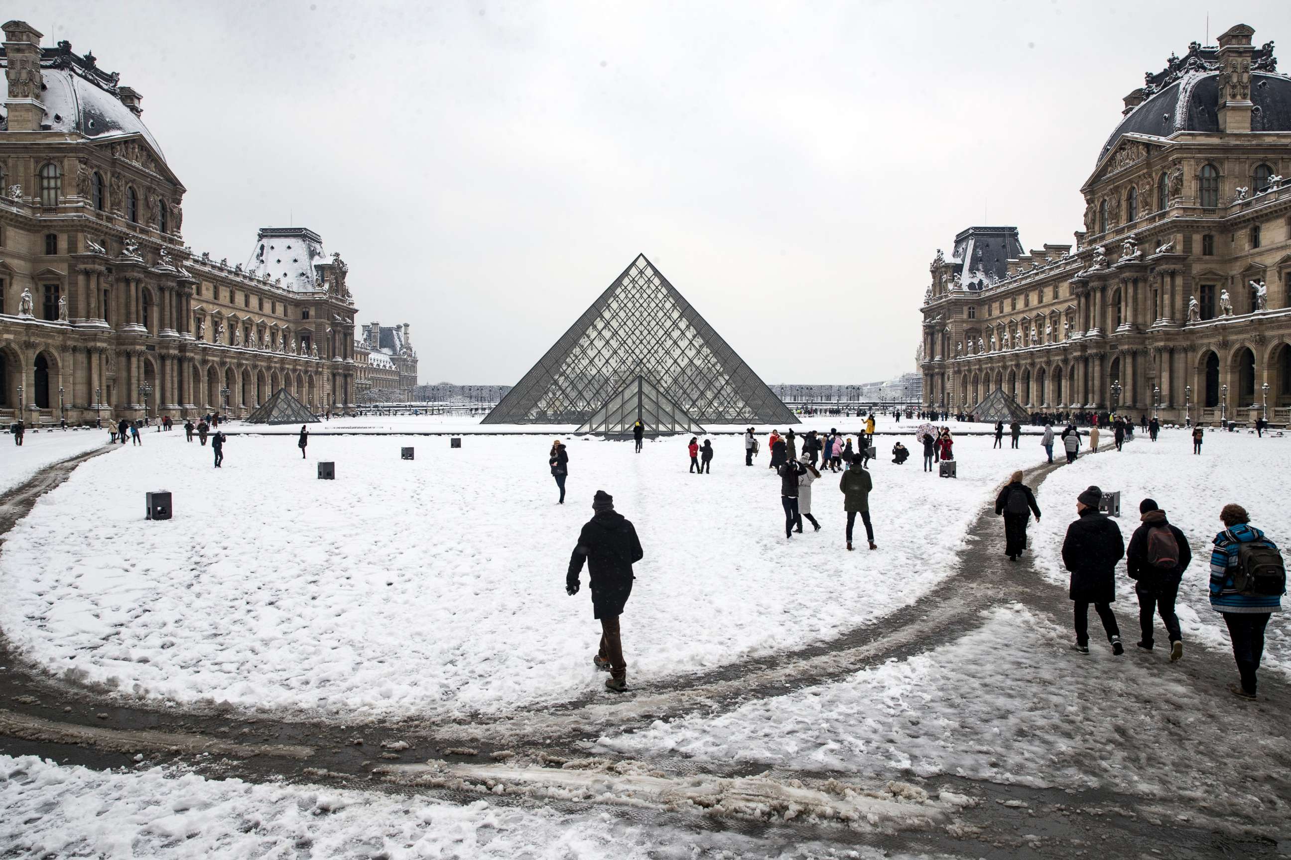 PHOTO: Tourists and Parisians walk in the snow next to the Louvre Pyramids in Paris, Feb. 7, 2018. 