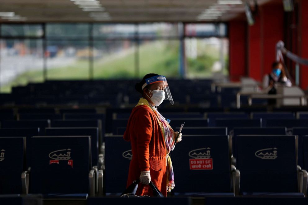 PHOTO: A passenger wearing personal protective equipment waits to board a flight at Tribhuvan International Airport in Kathmandu, Nepal, on Sept. 2, 2020.