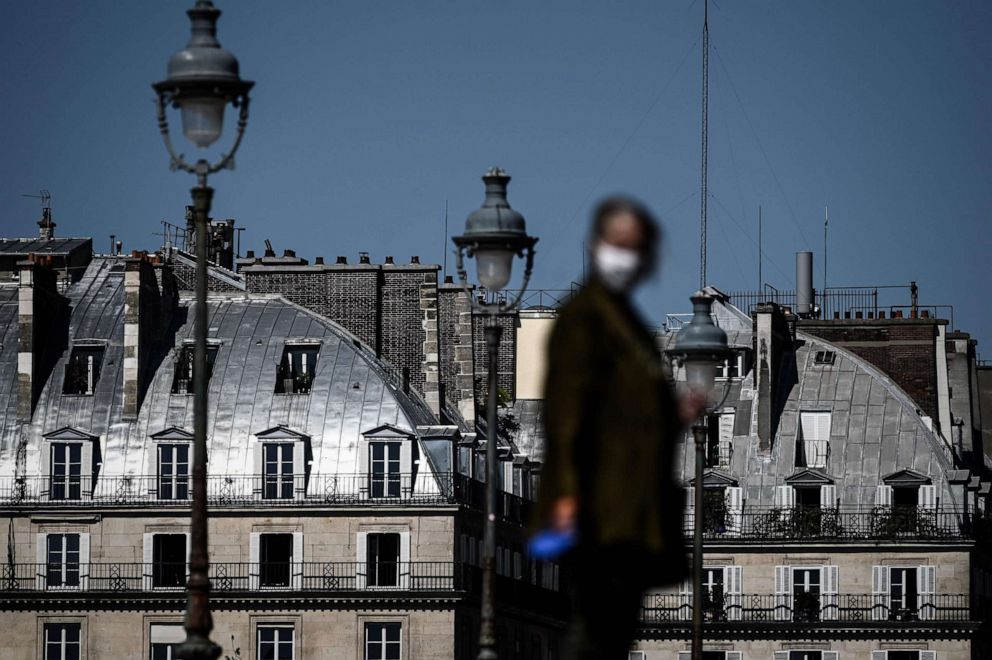 PHOTO: A woman wearing a protective mask looks on as she walks her dog during a sunny day in Paris, France, on April 26, 2020, as the country is under lockdown to stop the spread of the novel coronavirus.