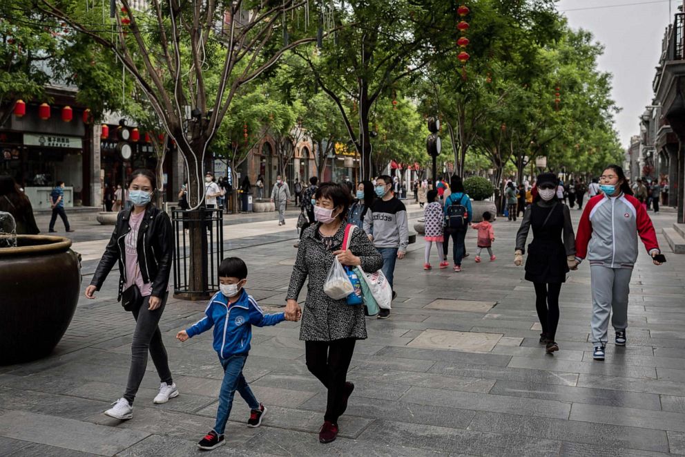 PHOTO: People wearing face masks as a preventive measure against the novel coronavirus walk on a street in Beijing, China, on May 4, 2020.