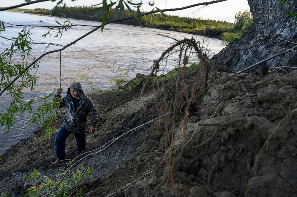 PHOTO: Andrei Danilov, a commercial truck driver and part time mammoth tusk hunter, walks below melting permafrost, right, in an area rich in mammoth tusks along the Kolyma River outside the Siberian town of Zyryanka, Russia on July 8, 2019.
