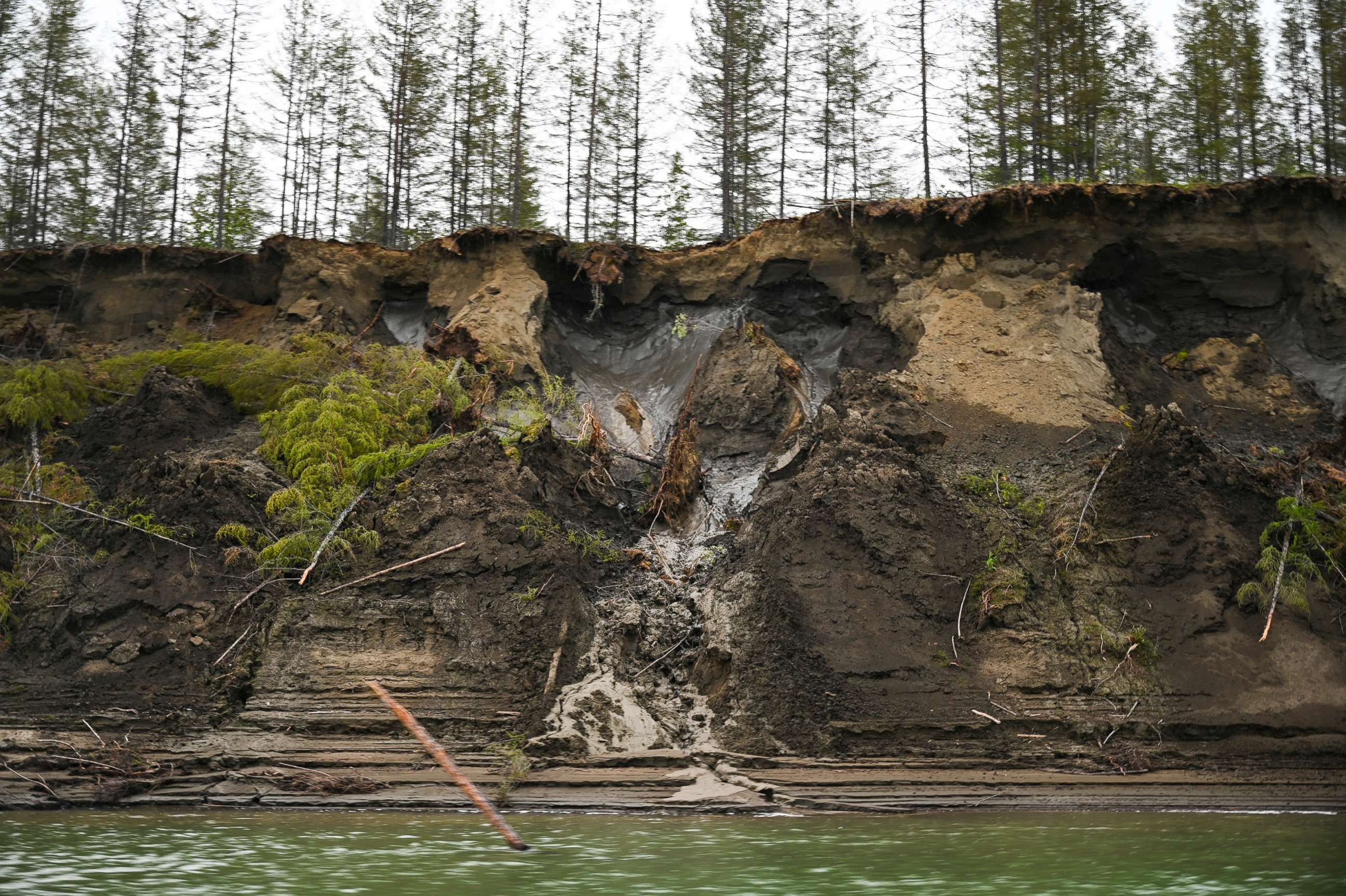 PHOTO: Permafrost, seen at the top of the cliff, melts into the Kolyma River outside of Zyryanka, Russia on July 4, 2019. The river is one of the principal rivers of Siberia and in summer, an essential transportation artery.