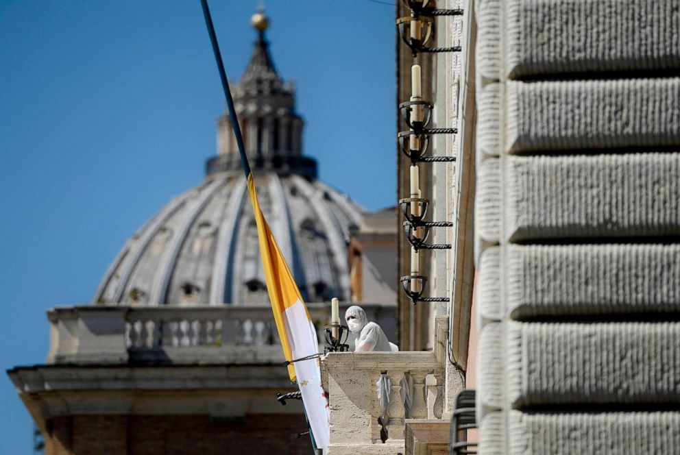 PHOTO: A person in protective gear stands at the balcony of a Vatican building on Via della Conciliazione in Rome on March 31, 2020, as flags are flown at half-mast in cities across Italy to commemorate the victims of the novel coronavirus.