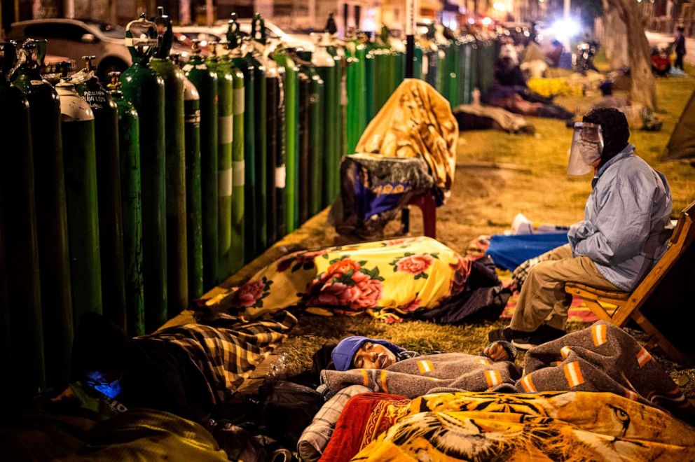 PHOTO: people queue to refill their empty oxygen cylinders on Jan. 29, 2021 amid the COVID-19 coronavirus pandemic in Callao, Peru.