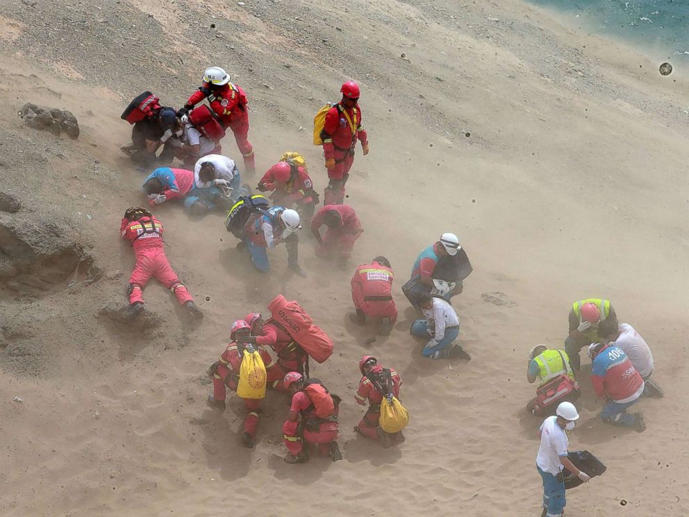 PHOTO: Emergency personnel covering themselves from dust generated by a helicopter during rescue operations after a passenger bus plunged off the Pan-American Highway North, outside of Lima, Peru, Jan. 2, 2018.