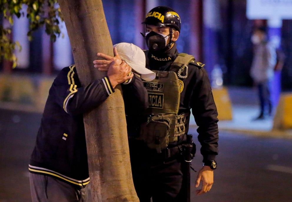 PHOTO: A police officers stands next to a man grieving the loss of a loved one, Aug. 23, 2020, outside the nightclub in Lima where at least 13 people suffocated in a stampede during a raid.