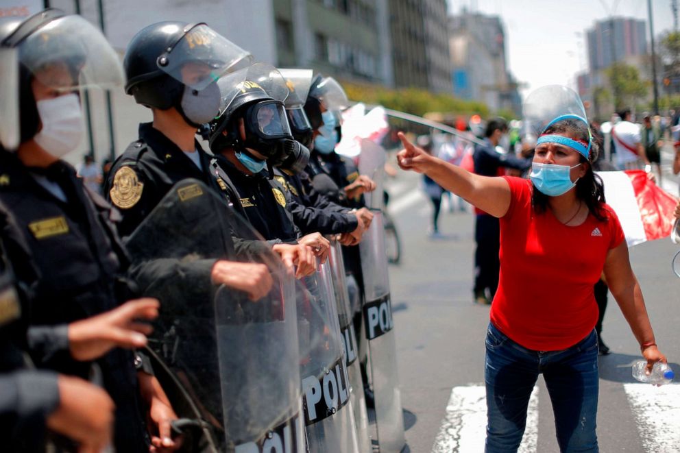 PHOTO: A woman gestures in front of police officers standing guard as people celebrate outside the Congress in Lima after Peruvian interim president Manuel Merino presented his resignation, Nov. 15, 2020.