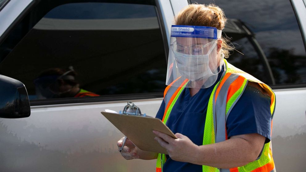 PHOTO: A nurse helps facilitate viral testing for COVID-19 at a federal surge testing site at Maryvale High School in Phoenix on July 17, 2020.