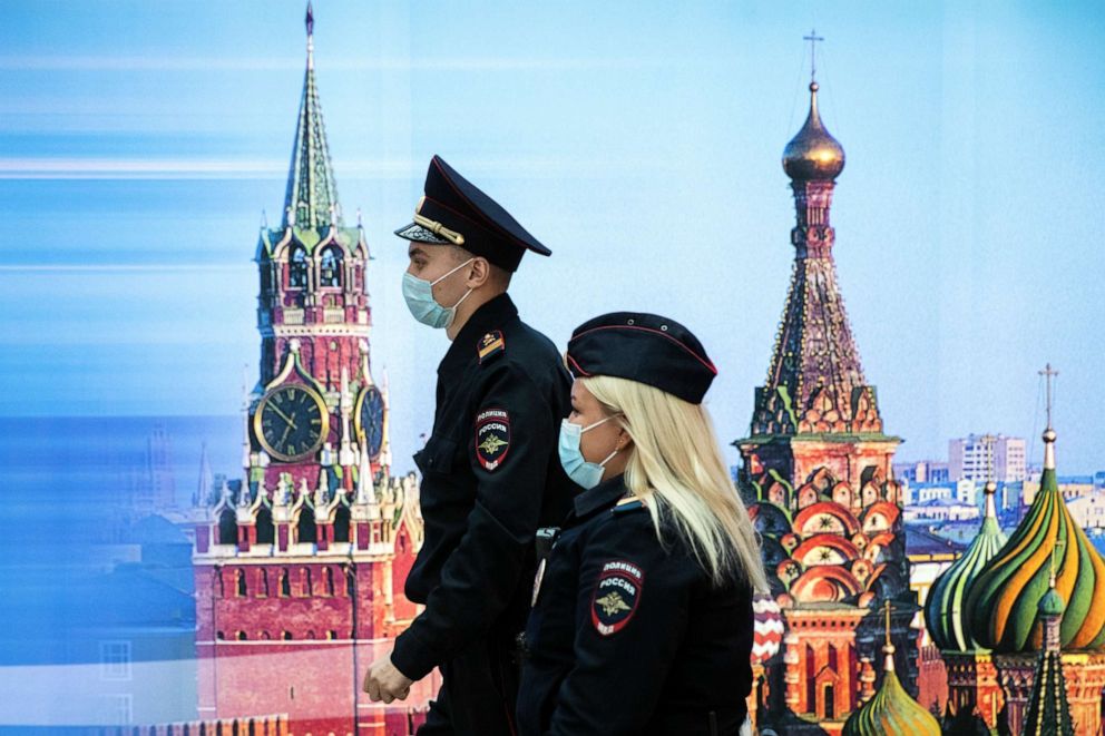 PHOTO: Police officers wearing face masks to protect against the novel coroanvirus walk past a photo of Kremlin's Spasskaya Tower (left) and St. Basil's Cathedral at Sheremetyevo airport, outside Moscow, Russia, on Oct. 9, 2020.