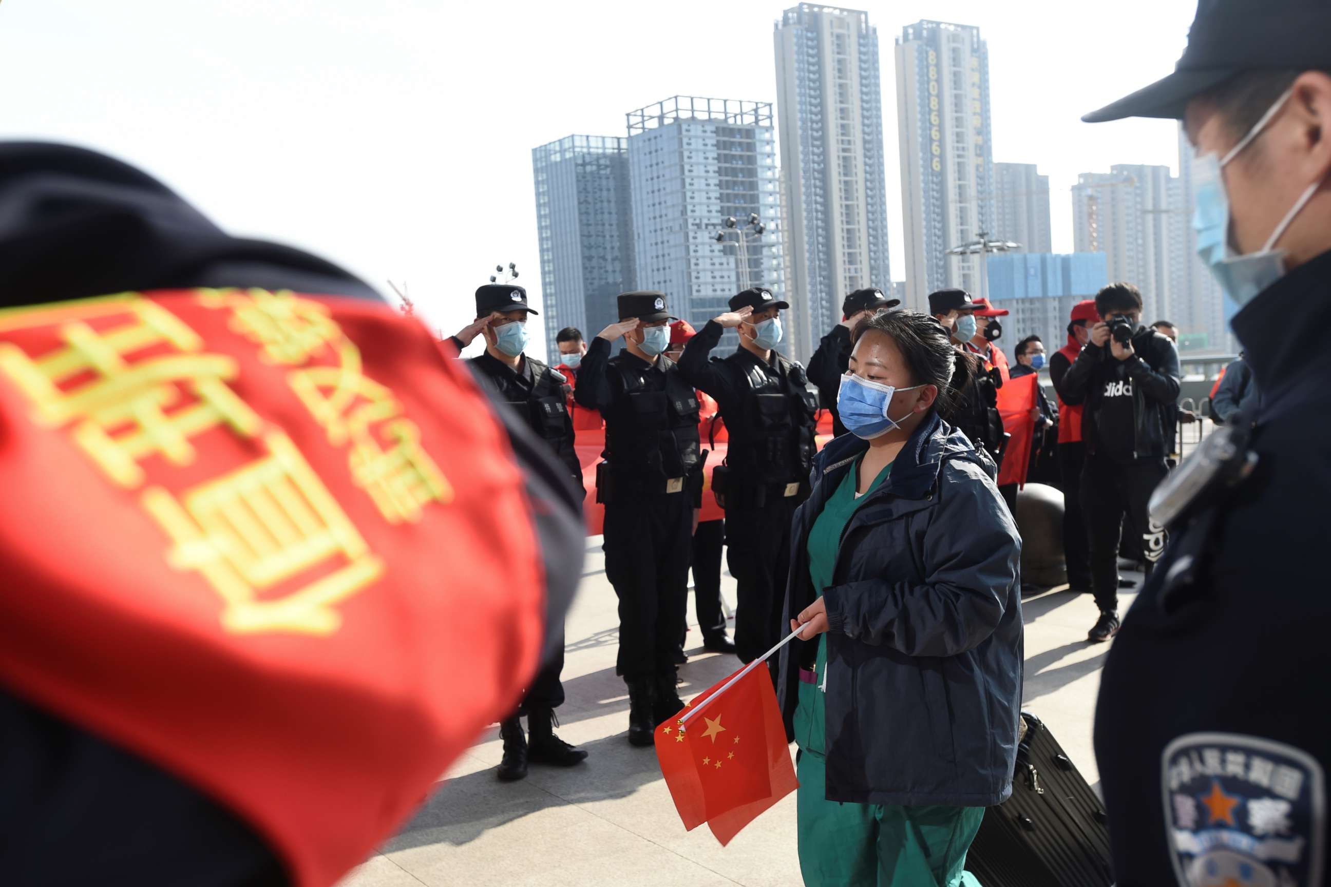PHOTO: Chinese police officers salute as a medical worker arrives at the Wuhan Railway Station before leaving the epicenter of the novel coronavirus outbreak, in the city of Wuhan in China's central Hubei province, March 17, 2020.