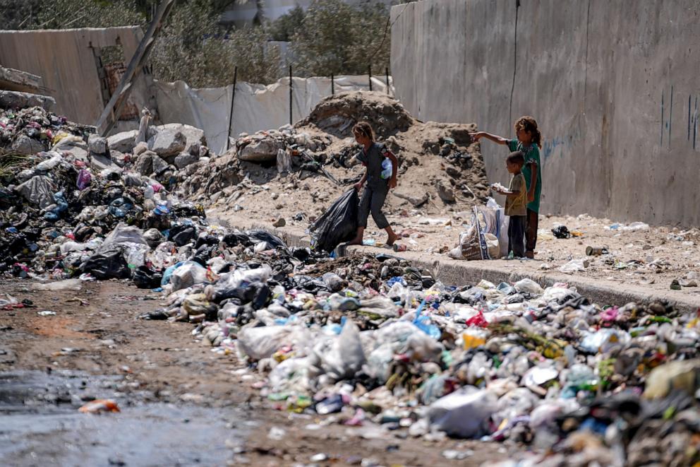 PHOTO: Displaced kids sort through trash at a street in Deir al-Balah, central Gaza Strip, Tuesday, Aug. 27, 2024.