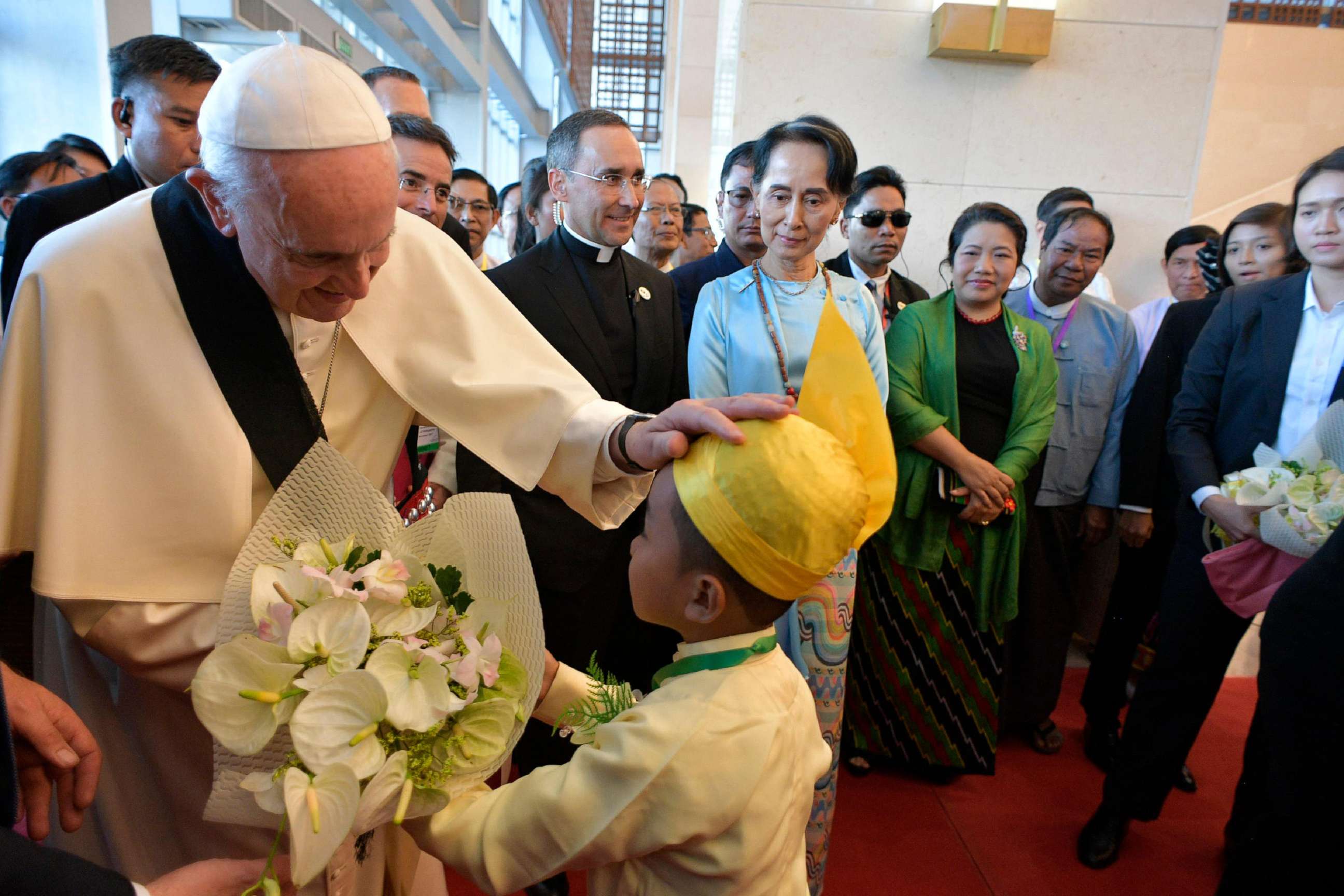 PHOTO: This handout picture taken and released by the Vatican press office (Osservatore Romano) on Nov. 28, 2017, shows Pope Francis greeting a child as Myanmar's civilian leader Aung San Suu Kyi watches during an event in Naypyidaw.
