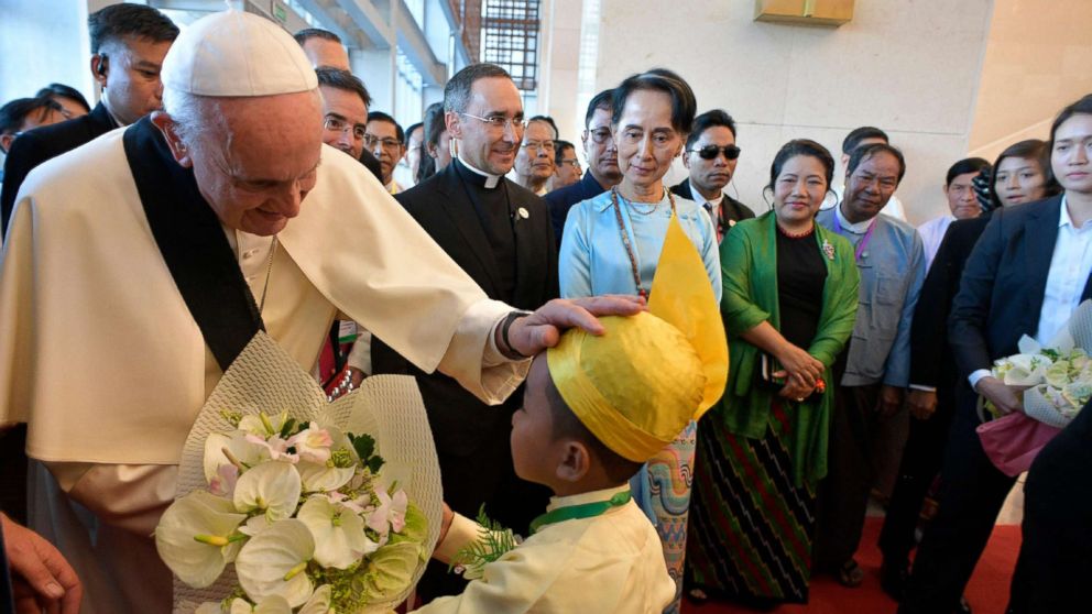 PHOTO: This handout picture taken and released by the Vatican press office (Osservatore Romano) on Nov. 28, 2017, shows Pope Francis greeting a child as Myanmar's civilian leader Aung San Suu Kyi watches during an event in Naypyidaw.