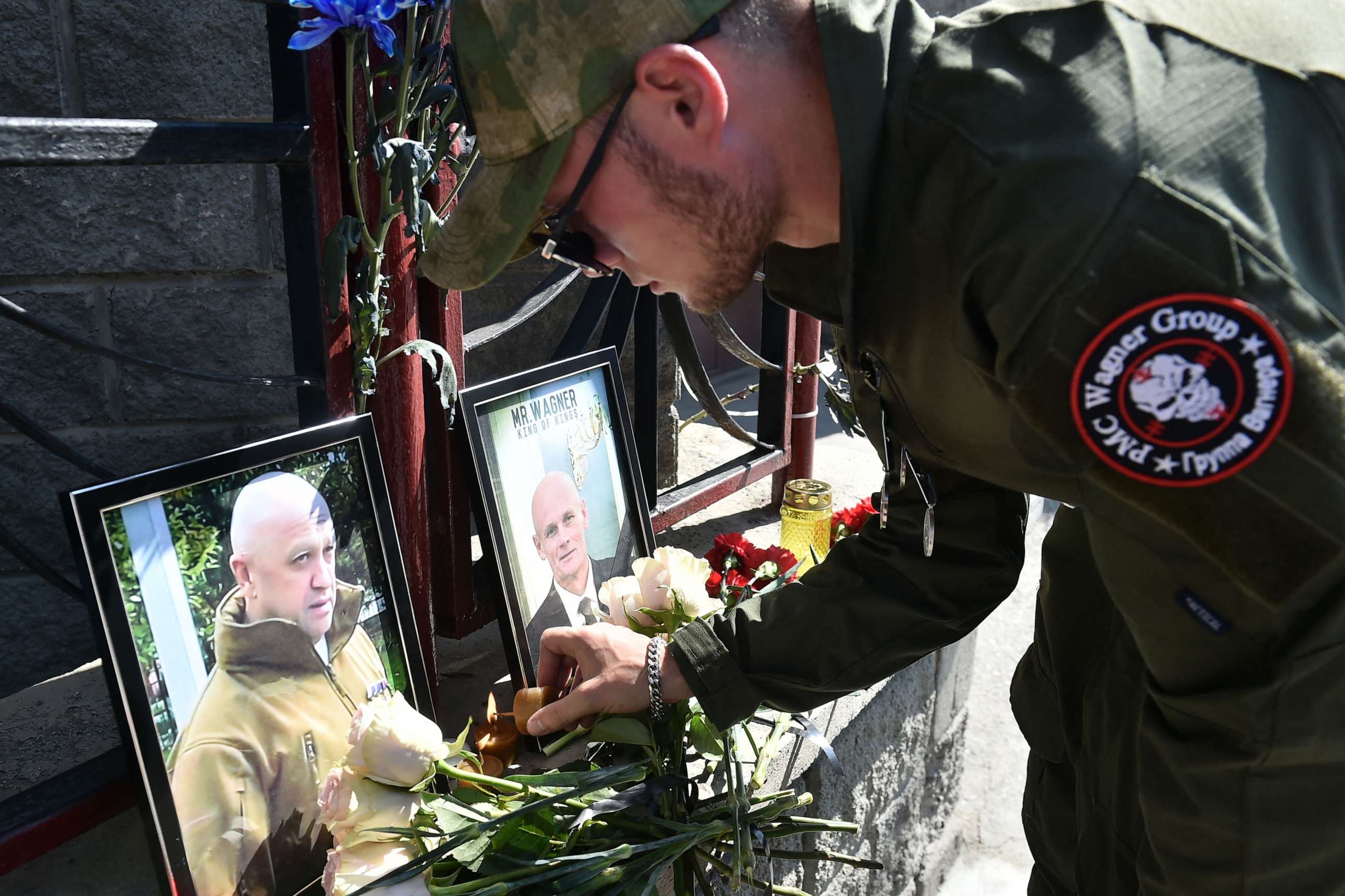 PHOTO: TOPSHOT - A member of private mercenary group Wagner pays tribute to Yevgeny Prigozhin (L) and Dmitry Utkin at the makeshift memorial in front of the PMC Wagner office in Novosibirsk, on August 24, 2023.