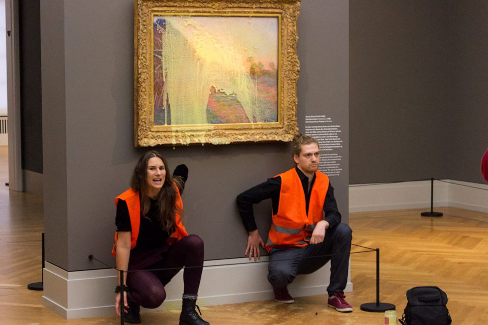 PHOTO: This handout picture released, Oct. 23, 2022, by "Last Generation" shows activists glued underneath the painting "Les Meules" by French artist Claude Monet after pouring mashed potatoes on the artwork in the Barberini Museum in Potsdam, Germany.