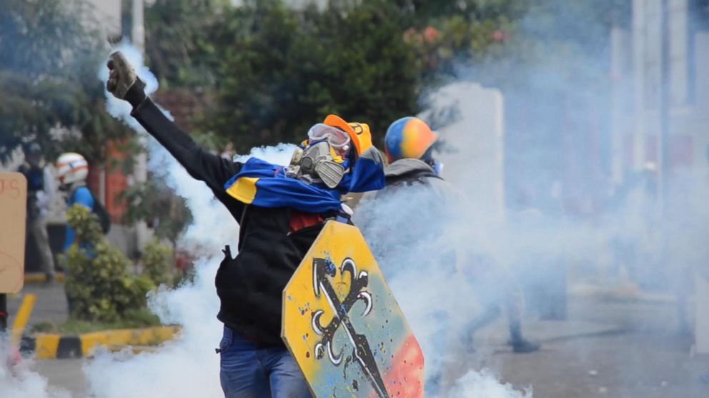 PHOTO: An anti-government demonstrator throws back a tear gas cannister launched by police forces, in Caracas, Venezuela.