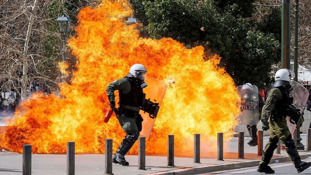FOTO: Seorang petugas polisi anti huru hara berjalan di samping api ketika bentrokan terjadi selama demonstrasi menyusul tabrakan dua kereta, di dekat kota Larissa, di Athena, Yunani, 5 Maret 2023.