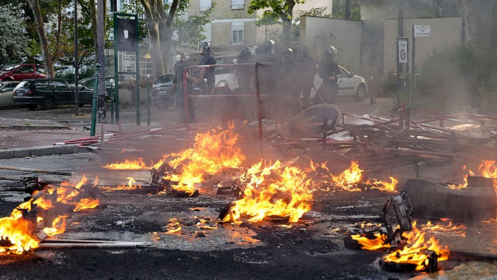 PHOTO: Police in riot gear stand next to a fire burning in the street after a protest in Nanterre, a suburb of Paris, France, on June 27, 2023.