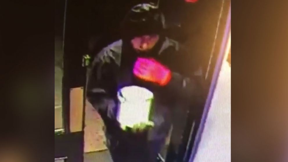 An image made from surveillance video shows a man entering a pub in Cheshire, England to throw a can of paint over the bar and its patrons.
