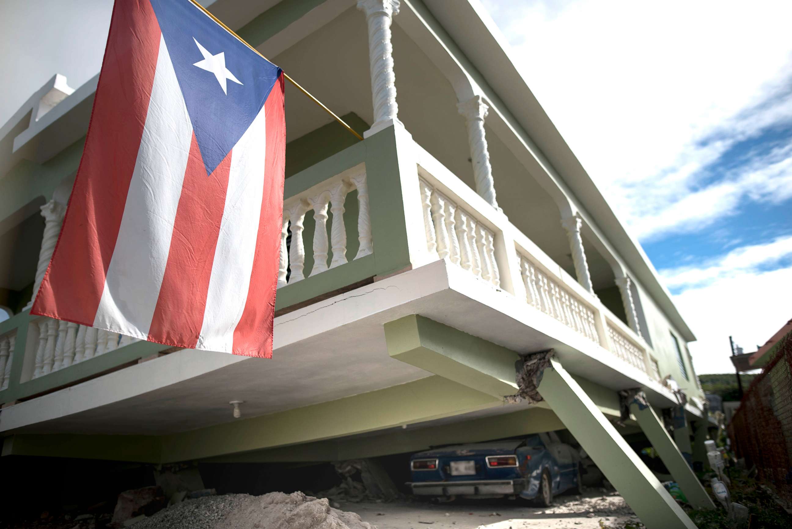 PHOTO: A Puerto Rican flag hangs from the porch of a home that collapsed on top of parked cars after an earthquake hit Guanica, Puerto Rico, Jan. 6, 2020.