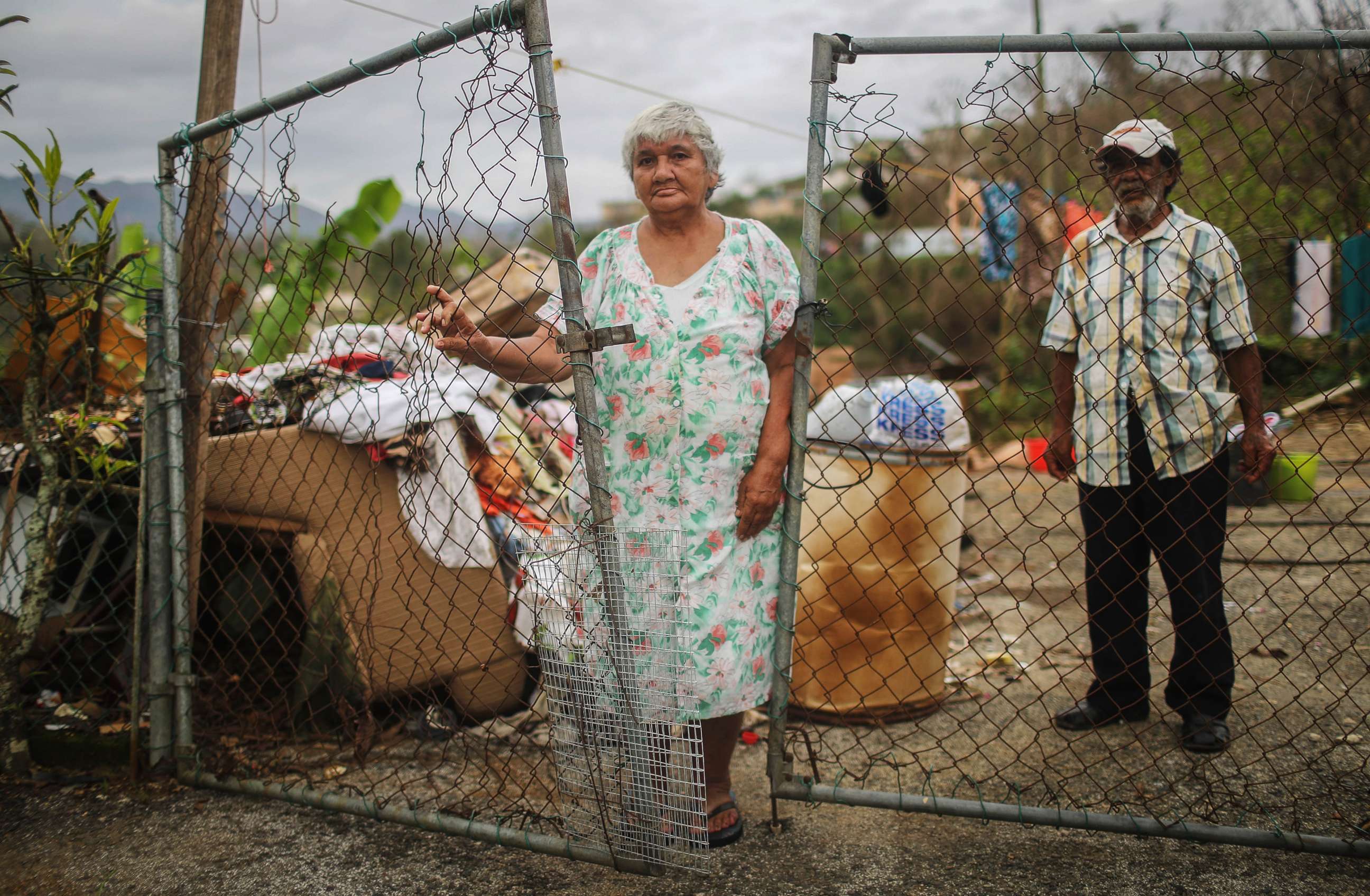 PHOTO: Luz Sota Rivera (C) and Francisco Nazario Aviles pose outside their damaged home, with debris removed from their home uncollected in the driveway, three weeks after Hurricane Maria hit the island, Oct. 12, 2017 in Jayuya, Puerto Rico. 