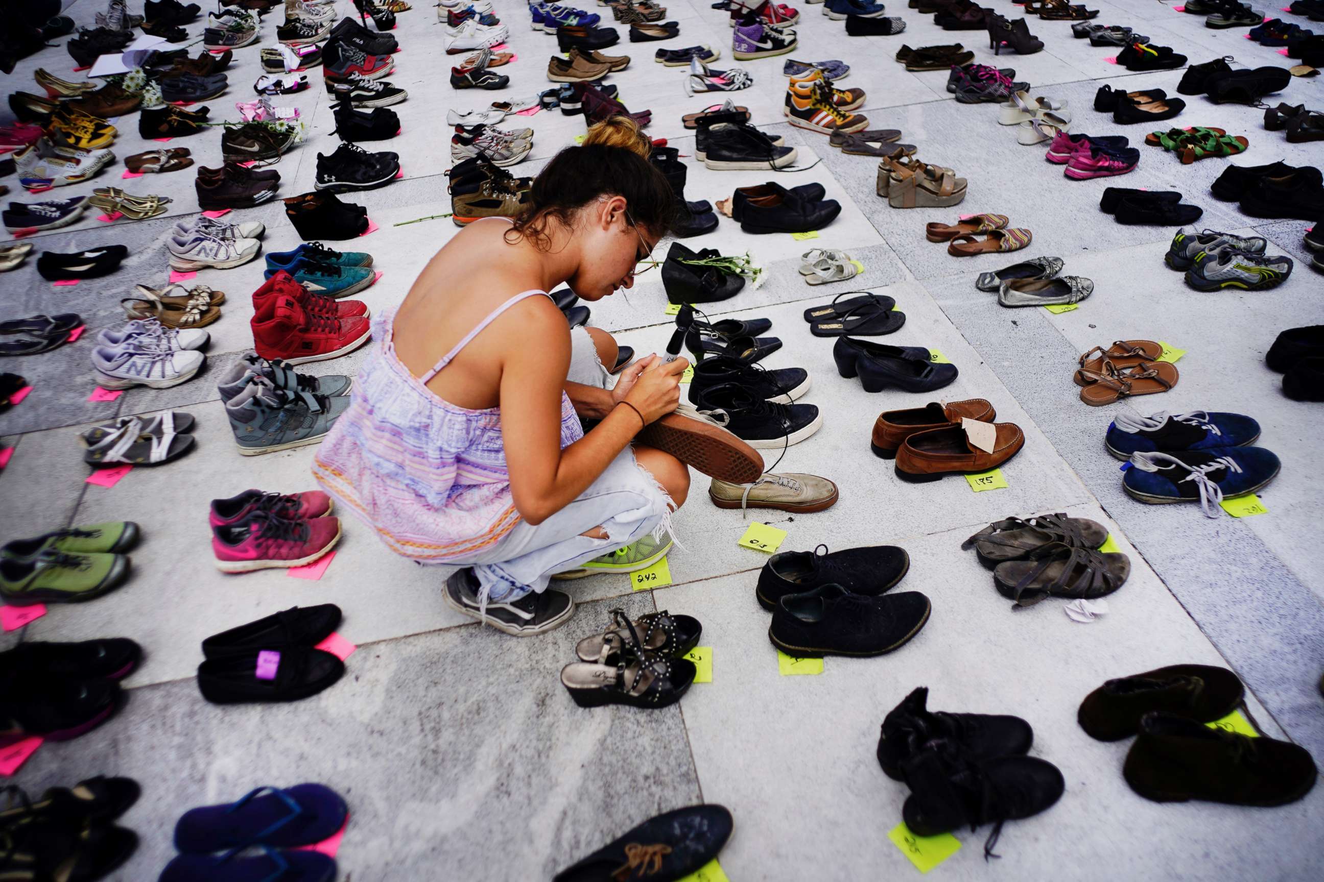 PHOTO: A woman places one of the hundreds of shoes in memory of those killed by Hurricane Maria in front of the Puerto Rico Capitol, in San Juan, June 1, 2018.