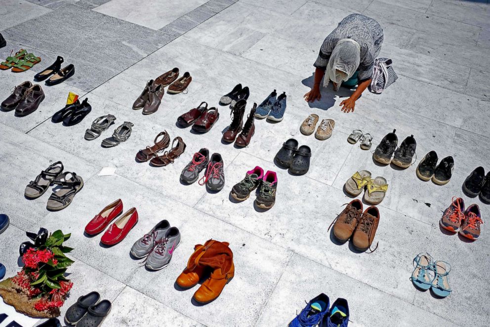 PHOTO: A woman prays in front of hundreds of shoes that were displayed in memory of those killed by Hurricane Maria in San Juan on June 1, 2018.