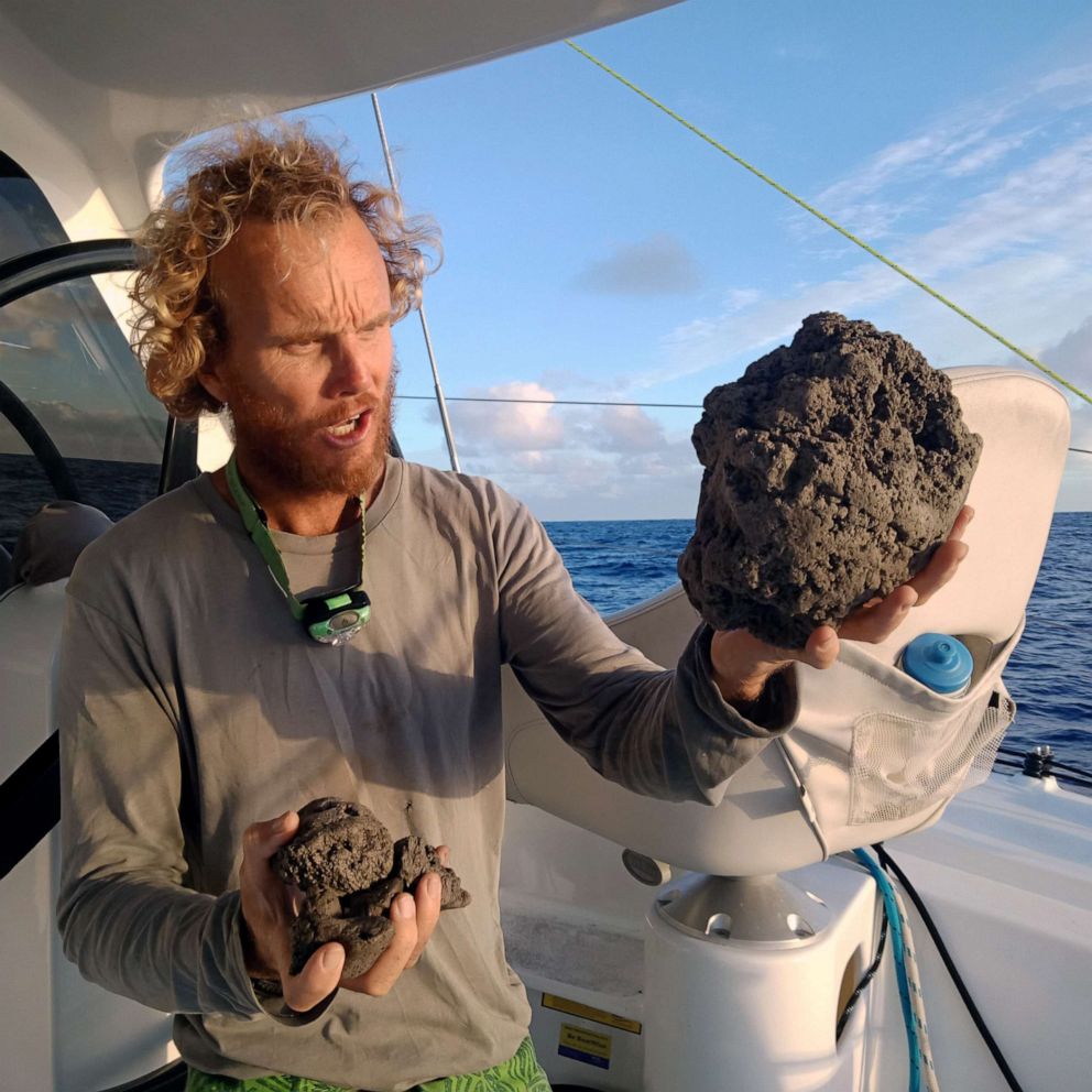 PHOTO: An undated handout photo made available by Sail Surf ROAM shows Michael Hoult holding pieces of pumice after collecting it from a large pumice raft near Tonga in the South Pacific Sea.