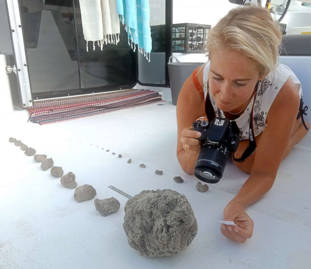 PHOTO: An undated handout photo made available by Sail Surf ROAM shows a woman documenting different sizes of pumice after collecting it from a large pumice raft near Tonga in the South Pacific Sea.