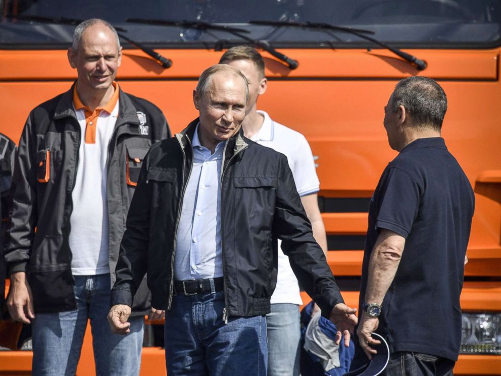 PHOTO: Russian President Vladimir Putin (C) talks to workers after driving a construction truck across the new 12 miles road-and-rail Crimean Bridge over the Kerch Strait that links mainland Russia to Moscow-annexed Crimea, May 15, 2018.