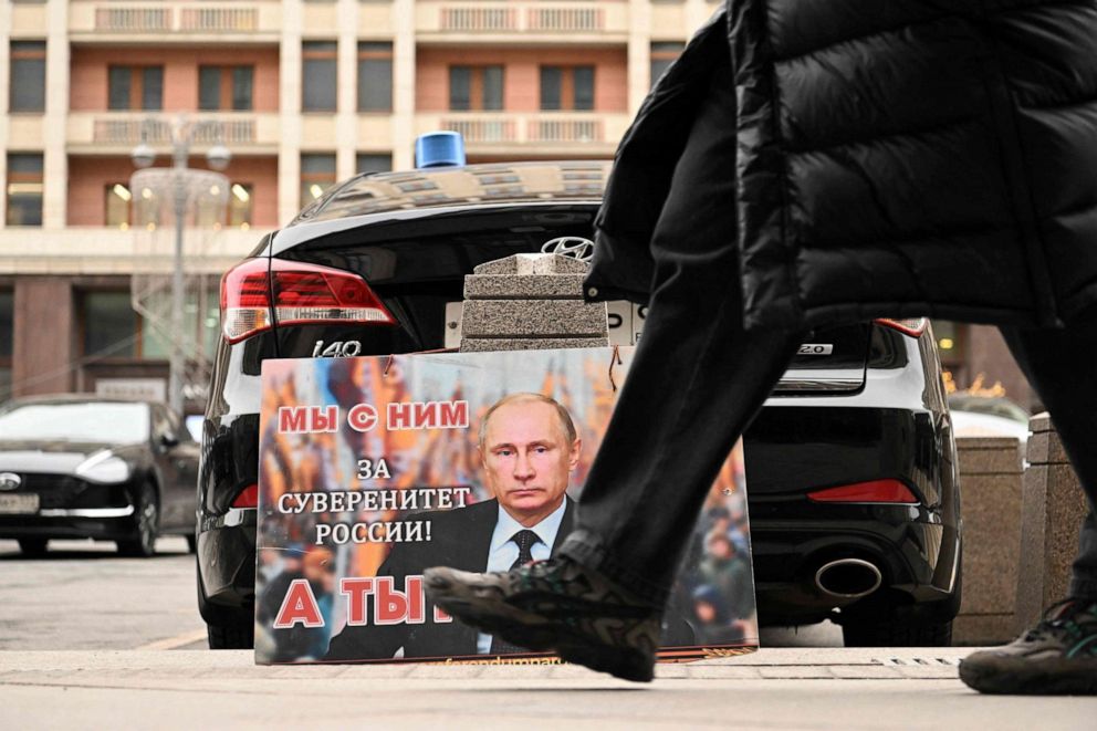 PHOTO: A placard featuring an image of Russian President Vladimir Putin with the words "We are with him for the sovereignty of Russia! And you?" is seen left in front of the Russian State Duma building in central Moscow on Feb. 24, 2022.