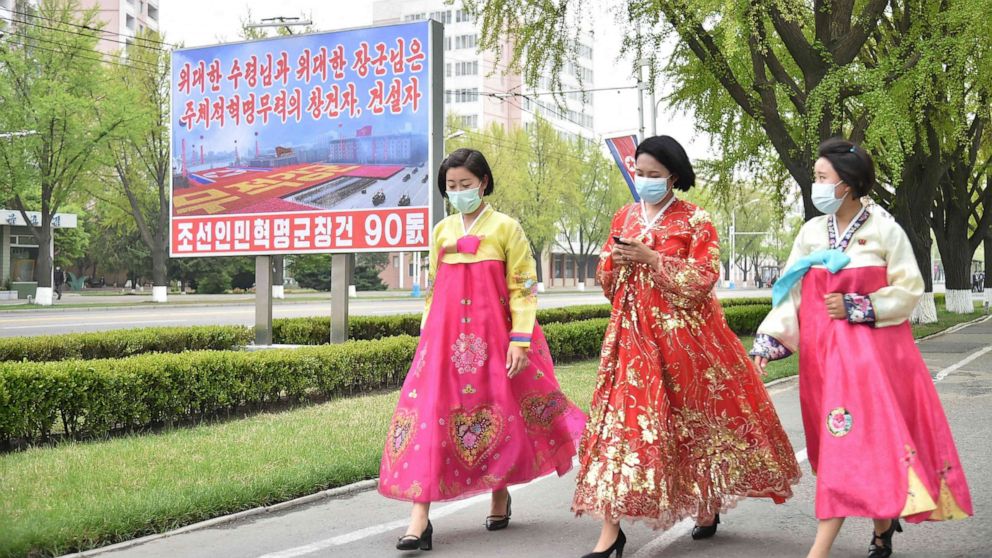 PHOTO: Women wearing traditional hanbok dresses walk past a billboard displayed to mark the 90th founding anniversary of the Korean People's Revolutionary Army in Pyongyang on April 25, 2022.