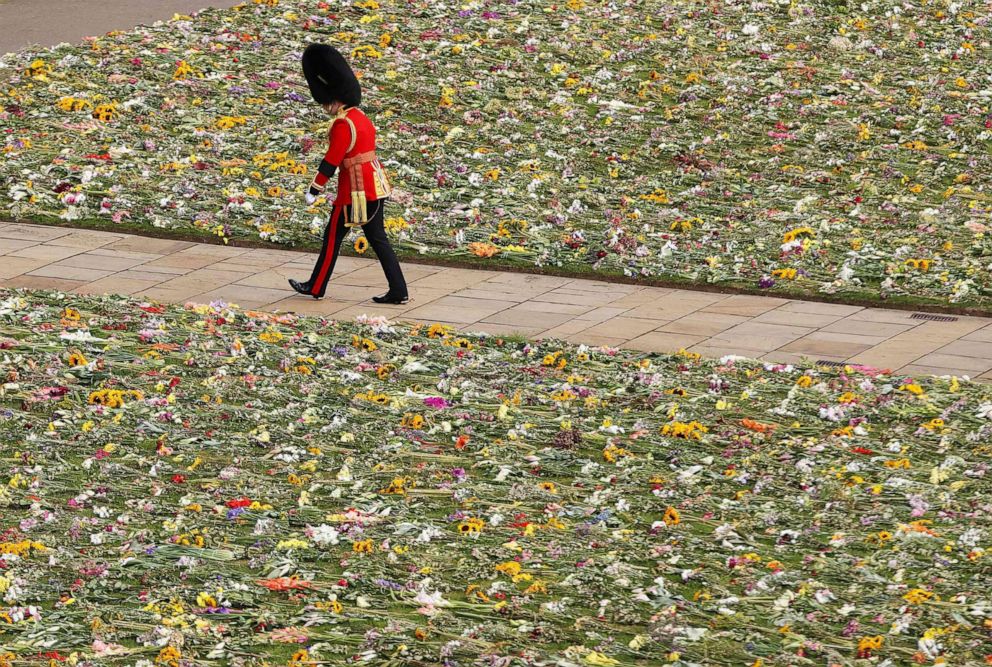 PHOTO: A member of the Coldstream Guards walks past flowers laid on the lawn outside Windsor Castle, during the State Funeral of Queen Elizabeth II, Sept, 19, 2022 in Windsor, England. 