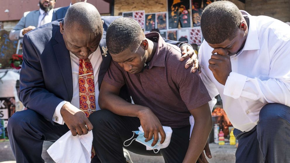 PHOTO: Quincy Mason Floyd, center, son of George Floyd, and attorney Ben Crump, left, kneel at the site where George Floyd was killed, on June 3, 2020, in Minneapolis, Minn.