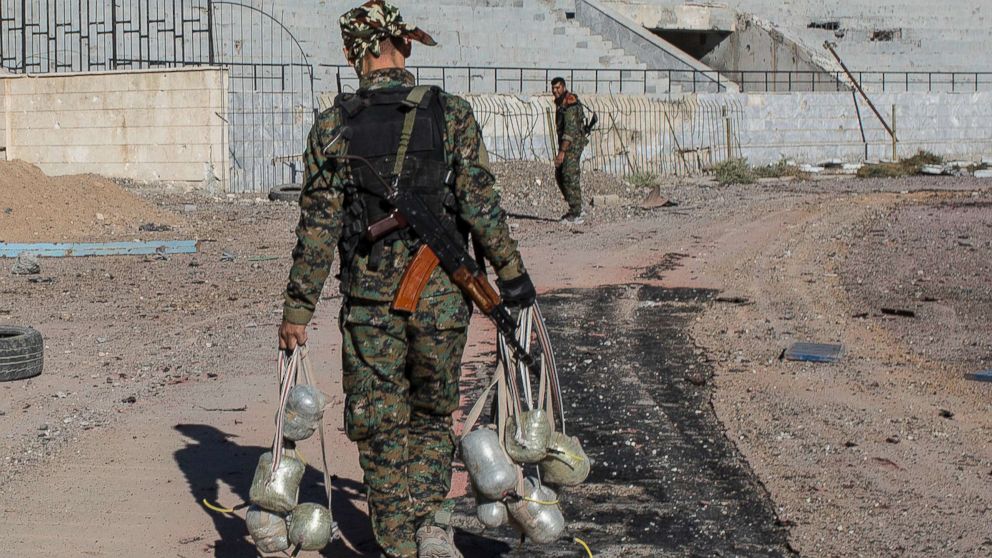 PHOTO: A member of the Syrian Democratic Forces carries bombs they use to destroy IEDs as they clear the stadium where it was the last stand for Islamic State fighters before most fighters handed in and left Raqqa, Syria on Oct. 18, 2017.