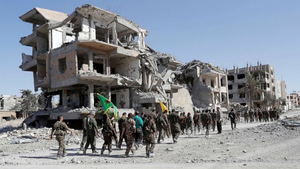 PHOTO: Fighters of Syrian Democratic Forces (SDF) march past destroyed buildings as they celebrate victory and liberation of Raqqa from the Islamic State militants, in Raqqa, Syria, Oct. 17, 2017. 