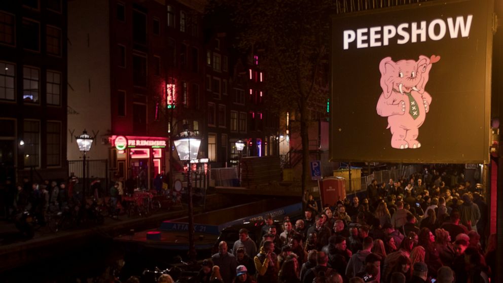 PHOTO: Tourists are bathed in a red glow emanating from the windows and peep shows' neon lights are packed shoulder to shoulder as they shuffled through the alleys in Amsterdam's red light district, Netherlands, Friday evening, March 29, 2019.