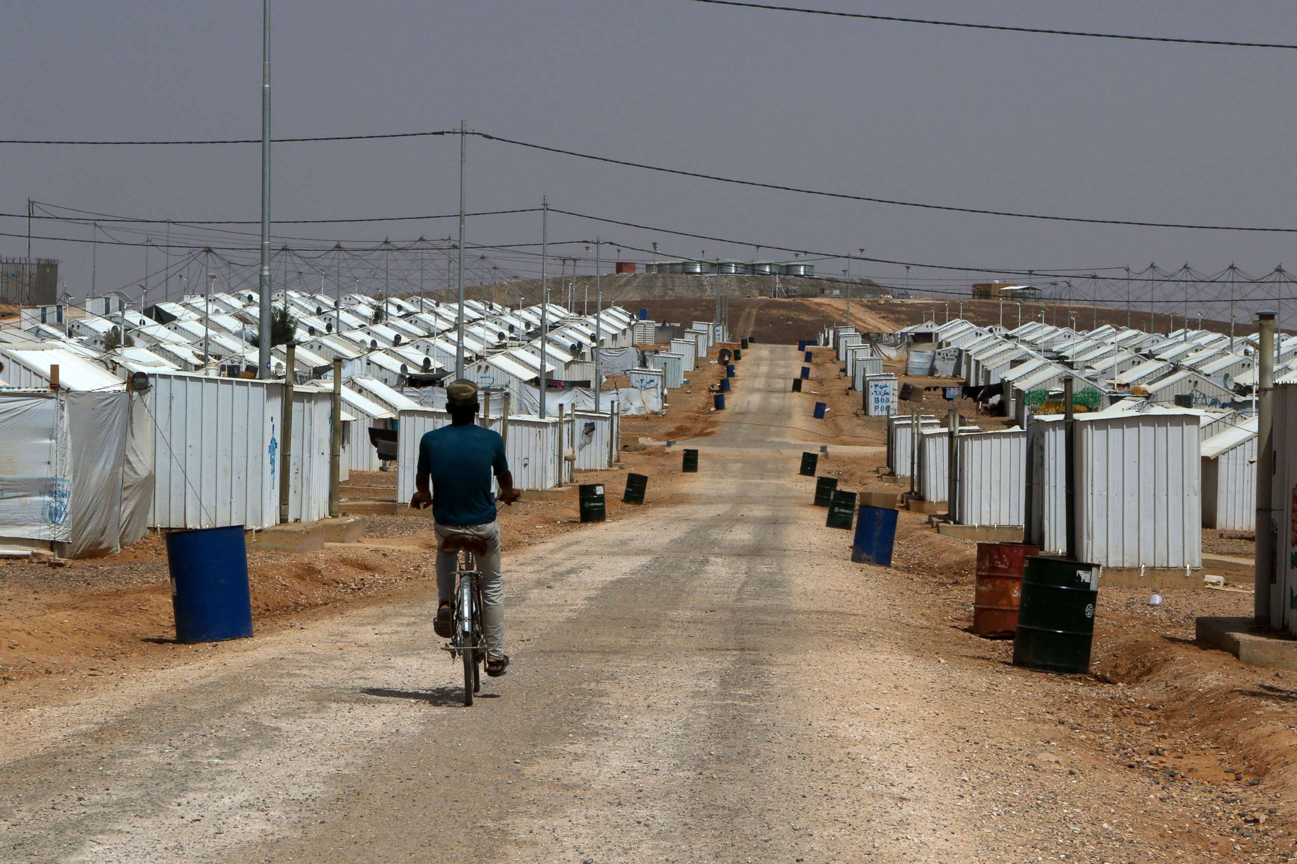 PHOTO: A Syrian refugee boy rides his bike under the hot sun near his makeshift home at the Azraq camp for Syrian refugees, the newest camp in Jordan that hosts 54.000 refugees in northeastern desert in Azraq, Jordan, July 13, 2017. 