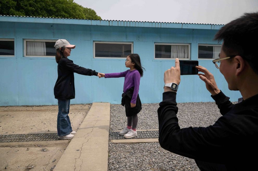 PHOTO: Visitors stand before a mock military demarcation line as they pose for photos at a replica of the DMZ border truce village of Panmunjom, built as a film set, near Namyangju, east of Seoul on May 5, 2018.