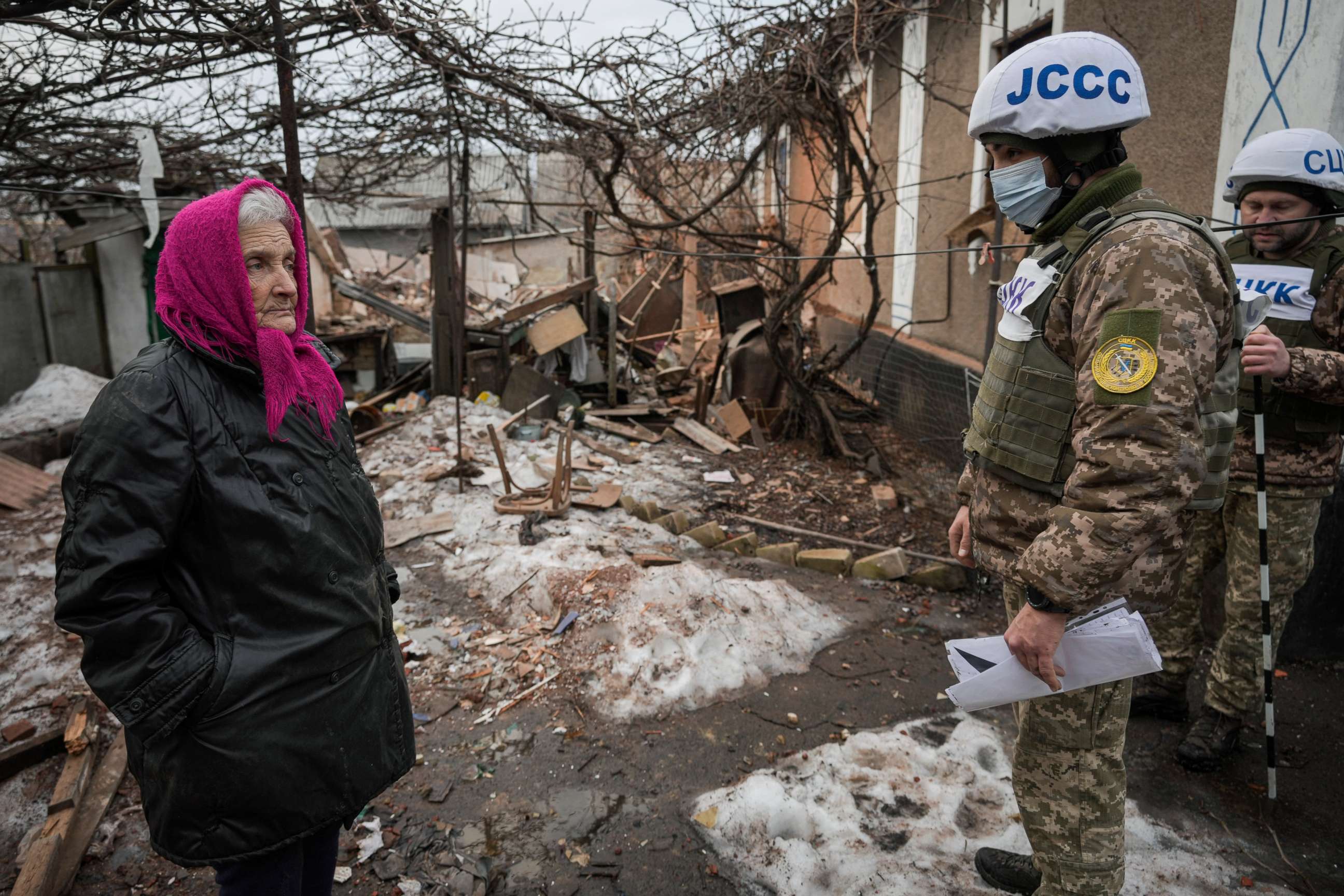 PHOTO: Valentyna Melnychenko listens to members of the Joint Center for Control and Coordination on ceasefire of the demarcation line (JCCC) surveying damage to her home from an artillery shell in Vrubivka, Luhansk region, eastern Ukraine, Feb. 17, 2022.